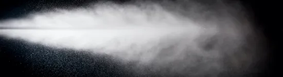 White mist or spray dispersing in the air against a dark background, creating a cloud-like effect.