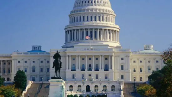 The United States Capitol building with its iconic dome, statue, and reflecting pool under a clear blue sky.