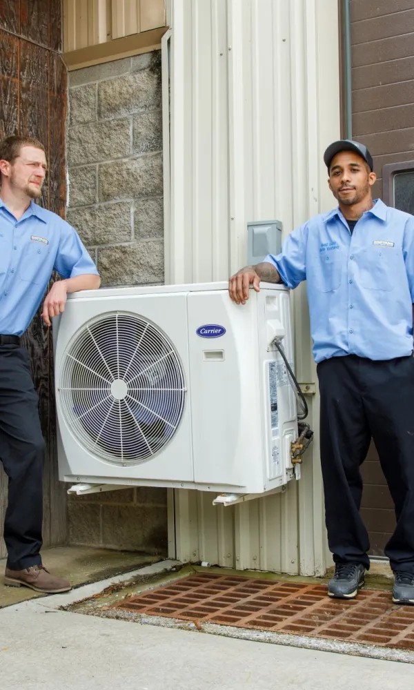 a couple of men standing outside a house with a fan