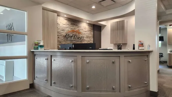 Modern reception area at Red Rocks Endodontics with curved desk, stone accent wall, and soft lighting.
