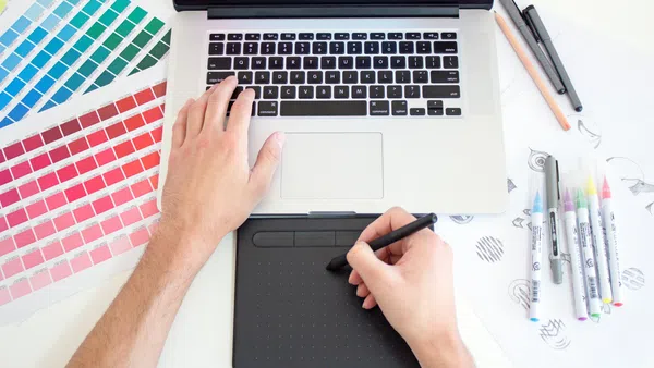 a person holding a pen and a laptop