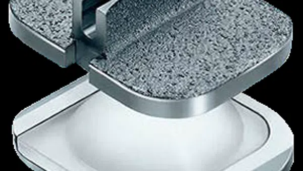 Close-up of a metal and plastic medical implant component with textured and smooth surfaces, isolated on black.