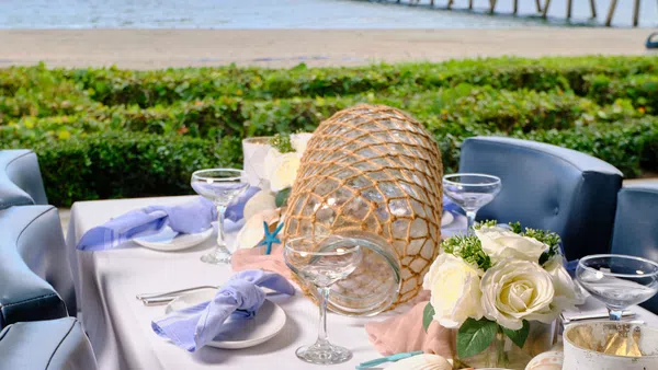 a table with glasses and plates on it by a beach