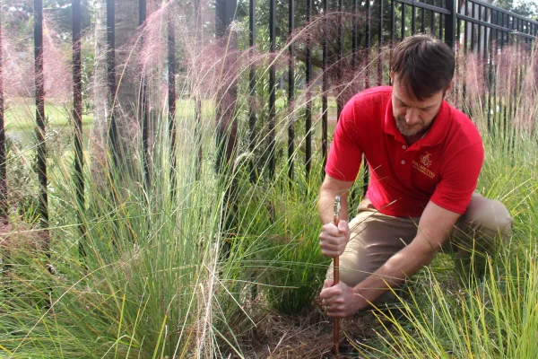 a man kneeling in a field of tall grass