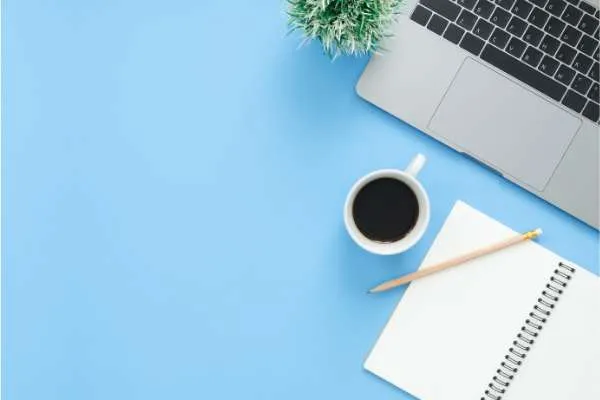 coffee, laptop, and notebook on blue desk