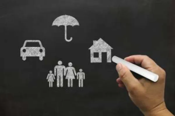 hand drawing an image on chalk board of home, family, and car under umbrella