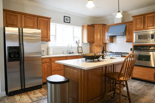 Modern kitchen with wooden cabinetry, stainless steel appliances, central island, and a wooden chair by the counter
