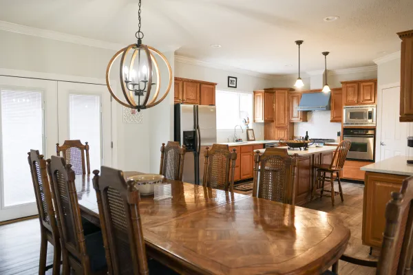 Spacious kitchen and dining area with wooden cabinets, large table, chandelier, and modern appliances.