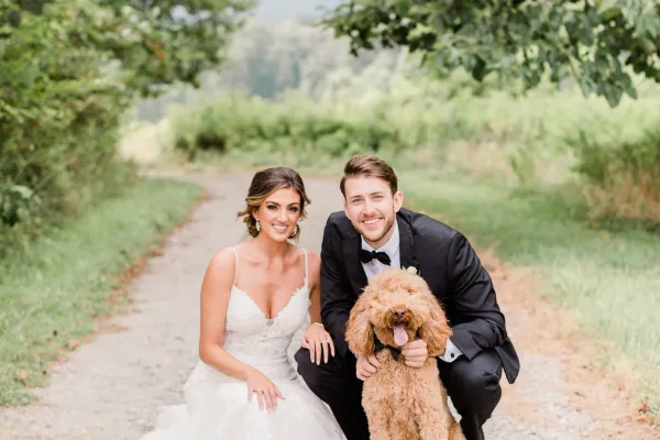 a man and woman in wedding attire holding a dog