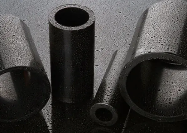 Close-up of wet black metal and plastic tubes of varying sizes on a dark reflective surface.