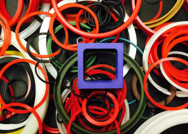 Colorful rubber rings and gaskets of various sizes with a prominent blue square ring in the center.