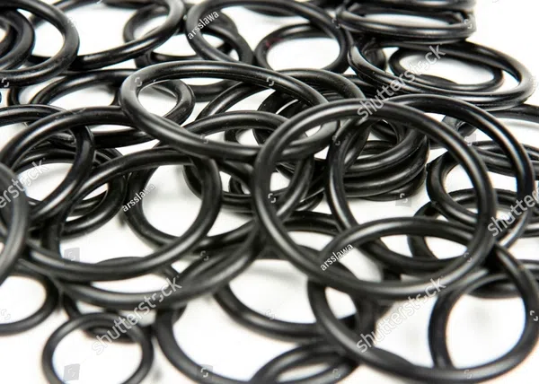 Close-up of multiple black rubber O-rings scattered on a white surface, showing their round shapes and texture.