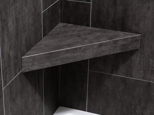Dark gray triangular corner shower shelf mounted on matching tiled wall above white shower base