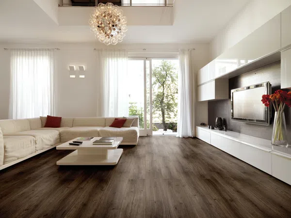 Bright modern living room with white sectional sofa, dark wood floor, minimalist coffee table, and large windows.