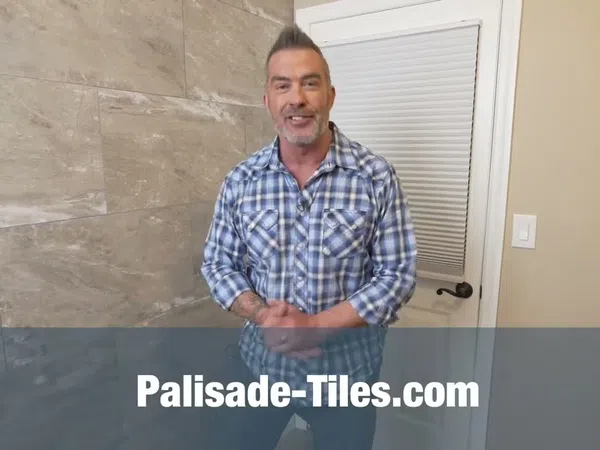 Man in blue plaid shirt stands in modern tiled room with Palisade-Tiles.com text overlay.