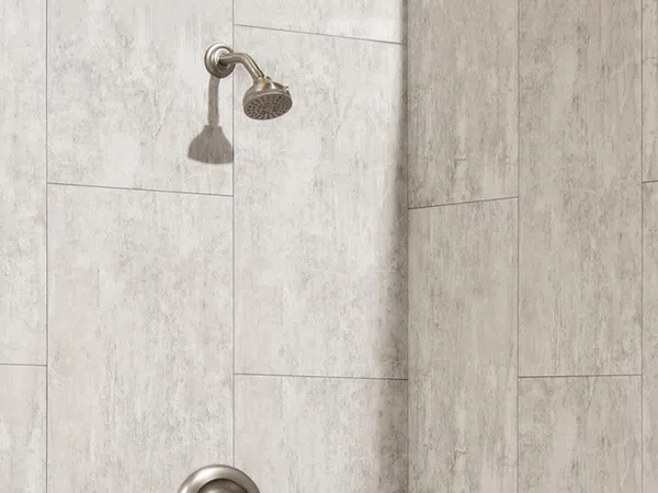 Modern bathroom shower with silver showerhead and light gray stone tile walls in rectangular pattern