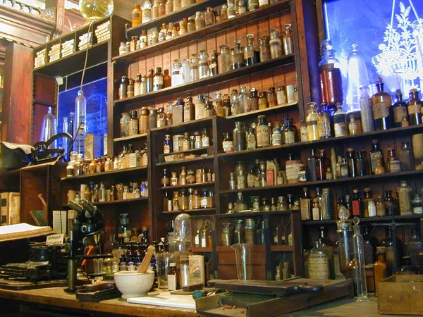 Shelves filled with vintage apothecary jars and bottles in an old-style pharmacy setting.