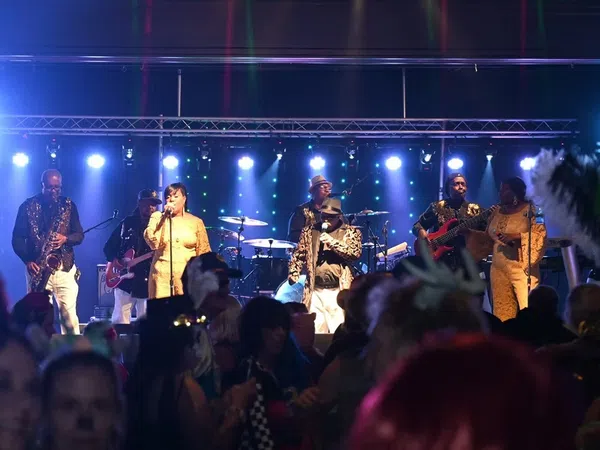 Live band performing on stage with vibrant blue lights and crowd enjoying the music at night event