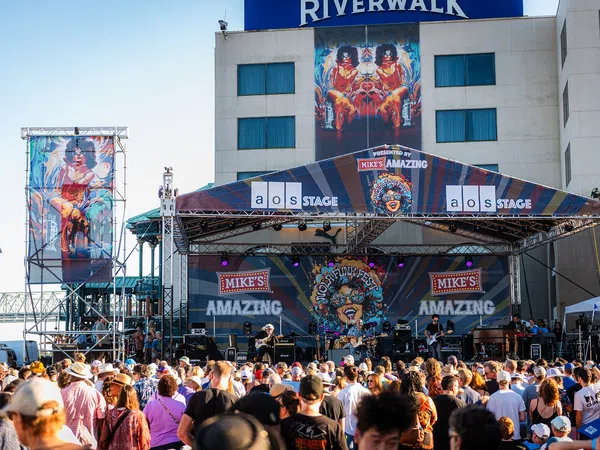 Outdoor music festival on Mike's Amazing stage at Riverwalk with large crowd enjoying live band performance.