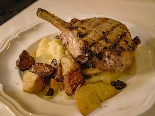 Grilled pork chop served with mashed potatoes and roasted vegetables on a white plate