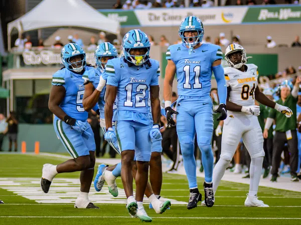 Tulane football players in blue uniforms celebrating on the field during a game against Southern University.