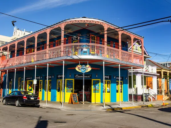 Colorful two-story building with yellow and blue walls and pink balcony railing at street corner in sunny weather