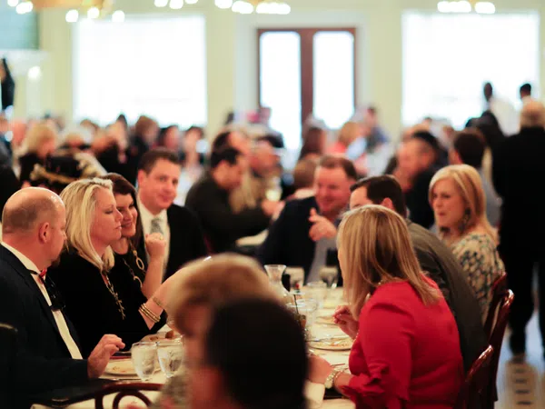 People enjoying a social gathering at a restaurant with conversations and dining in a warm, well-lit atmosphere.