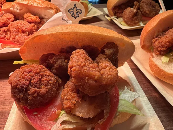 Close-up of fried shrimp po'boy sandwiches with lettuce and tomato on buns on wooden table