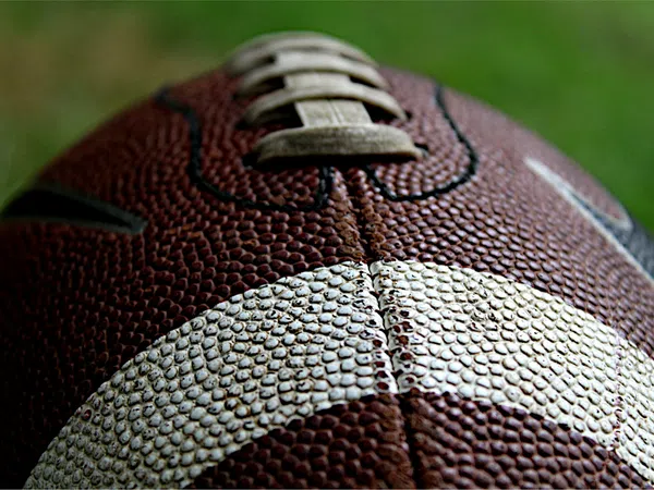 Close-up of a textured brown and white American football showing laces and pebbled surface detail.