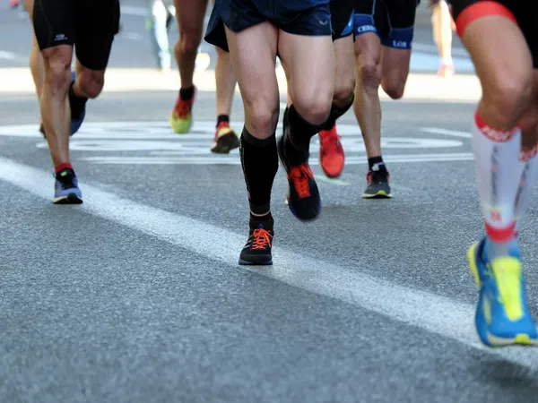 Close-up of runners' legs and feet in athletic shoes on a city road during a race event