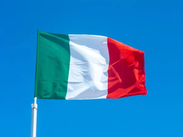 Italy national flag waving against a clear blue sky background outdoors.