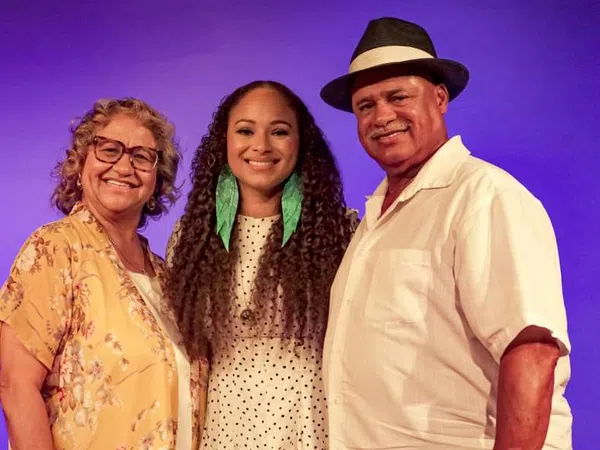 Smiling three generations family portrait with purple background and casual summer clothing