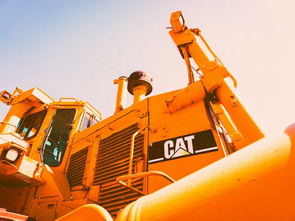 Close-up of a yellow Caterpillar bulldozer with visible CAT logo under bright sunlight.