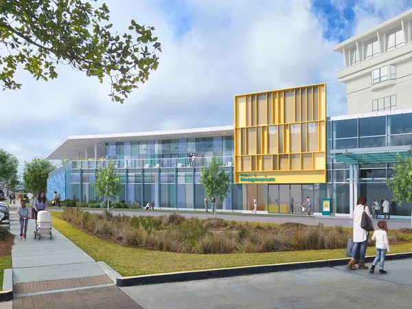 Modern imaging center with glass facade, yellow accent panels, landscaped front, and people walking outside.