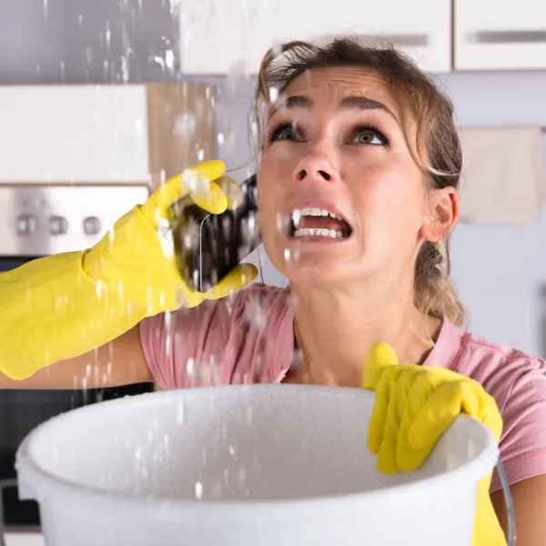 a woman catching water from a leak