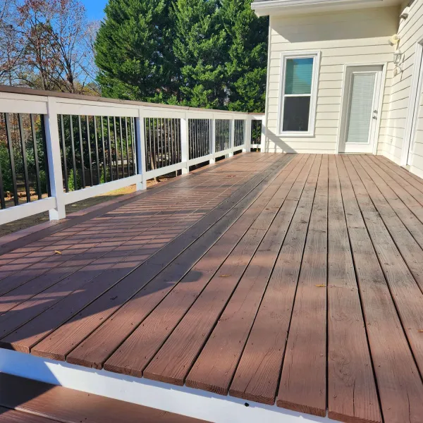 a deck with a wood railing and a house in the background