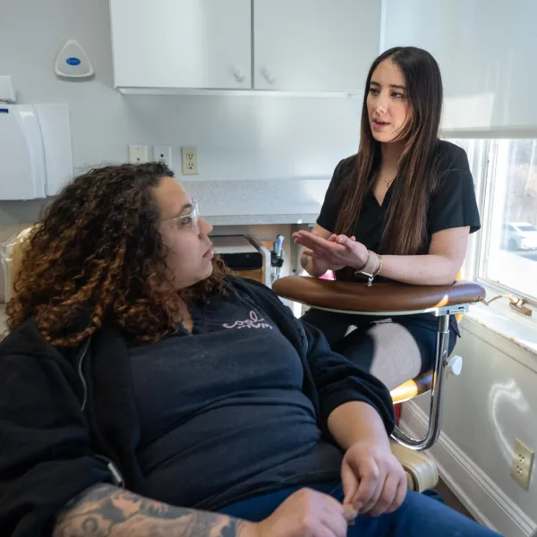 Two women engaged in a discussion in a bright clinical or office setting near a window