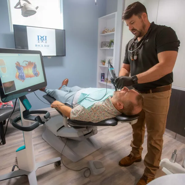 Dentist performing dental treatment on patient in modern clinic with digital imaging technology nearby