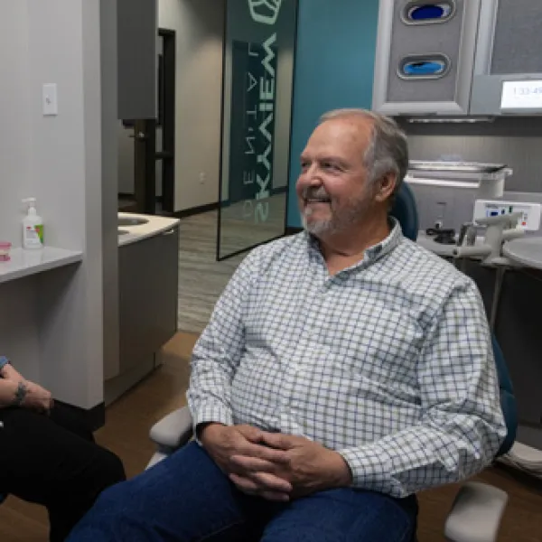 Dentist and patient smiling while sitting and talking in a modern dental clinic room.