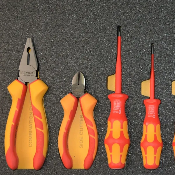 Set of insulated hand tools including pliers and screwdrivers with yellow and red handles on a dark background