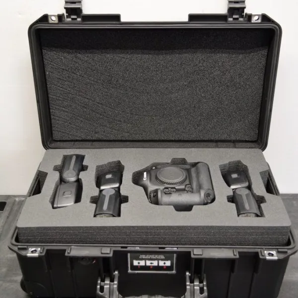 Black protective case with foam insert holding a camera body and accessories for secure transport.