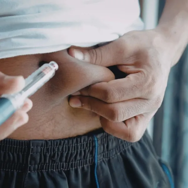 Person administering insulin injection into abdominal fat for diabetes management