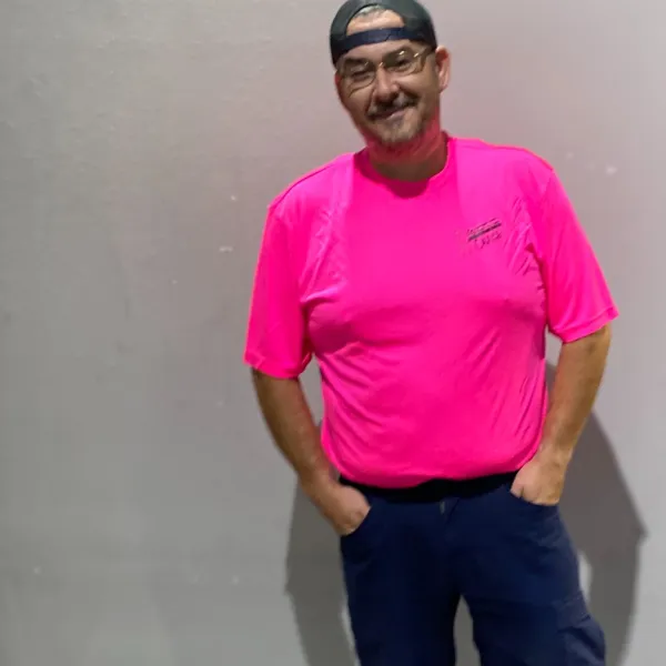 a man wearing a pink shirt and blue jeans