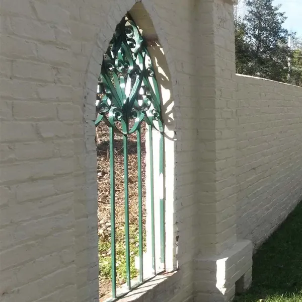 a stone wall with a gate and a car parked on the side