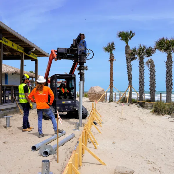 Cantsink workers installing helical piles for outdoor beach deck expansion