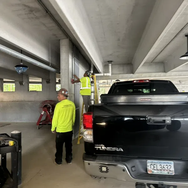 Construction workers in safety gear working on a building interior near a black Toyota Tundra pickup truck.