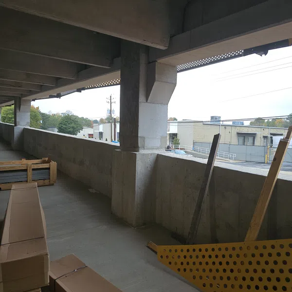 Concrete building under construction with stacked cardboard boxes and construction materials on outdoor balcony.