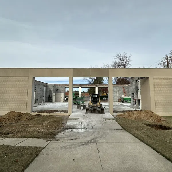 Partially constructed building with concrete and brick walls, construction equipment, and clear sky overhead.