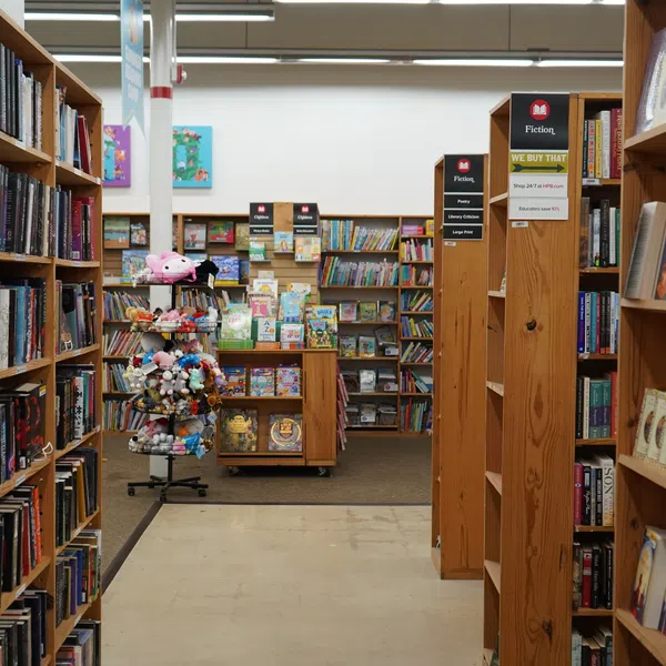 Interior view of a bookstore aisle with shelves filled with books and a display of toys and kids' books.