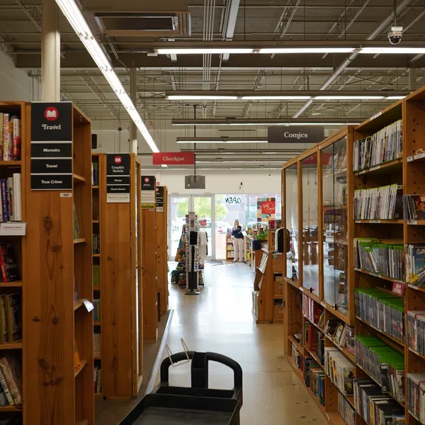 Interior of a bookstore showcasing aisles of books with signage for Travel, Comics, and Graphic Novels sections.